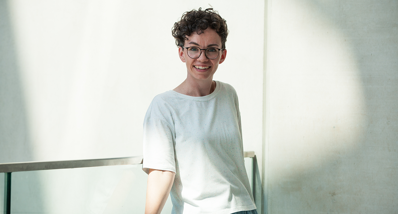 Verena Smit lehnt sich an ein Treppengeländer und lächelt direkt in die Kamera.