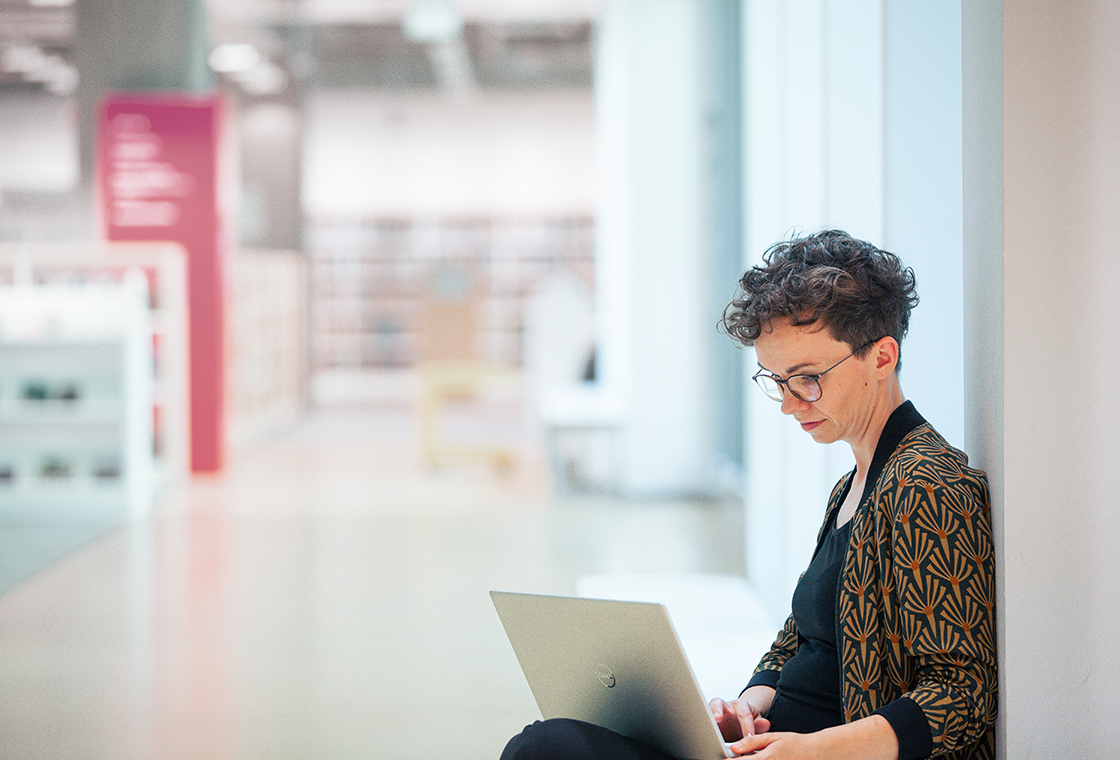 Verena Smit nimmt mit dem Laptop auf dem Schoß von unterwegs online an einer Redaktionskonferenz teil.
